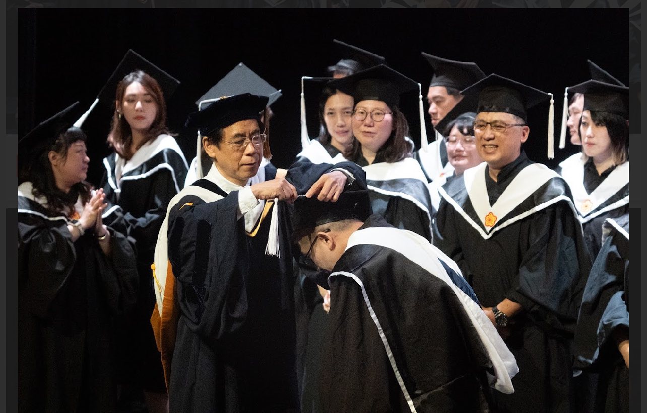 Executive Director Yae-Wei Wang of the Executive MA Program in Communication turns the tassel for graduates.